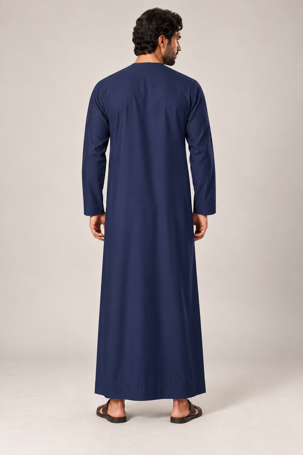 Back view of a male model wearing the navy blue Emirati thobe with a straight full-length silhouette