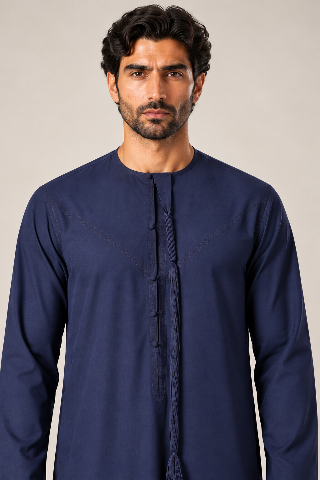Close-up of navy blue Emirati thobe showing the round neckline, long sleeves and hanging tassel detail